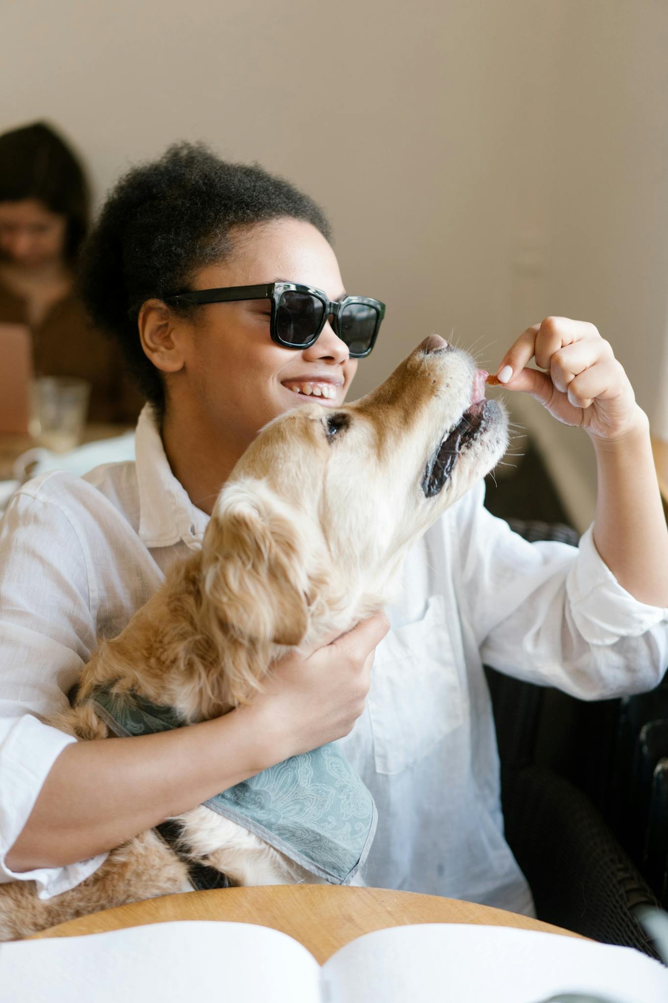 African American woman playing with her golden retriever indoors, sharing a joyful bond.